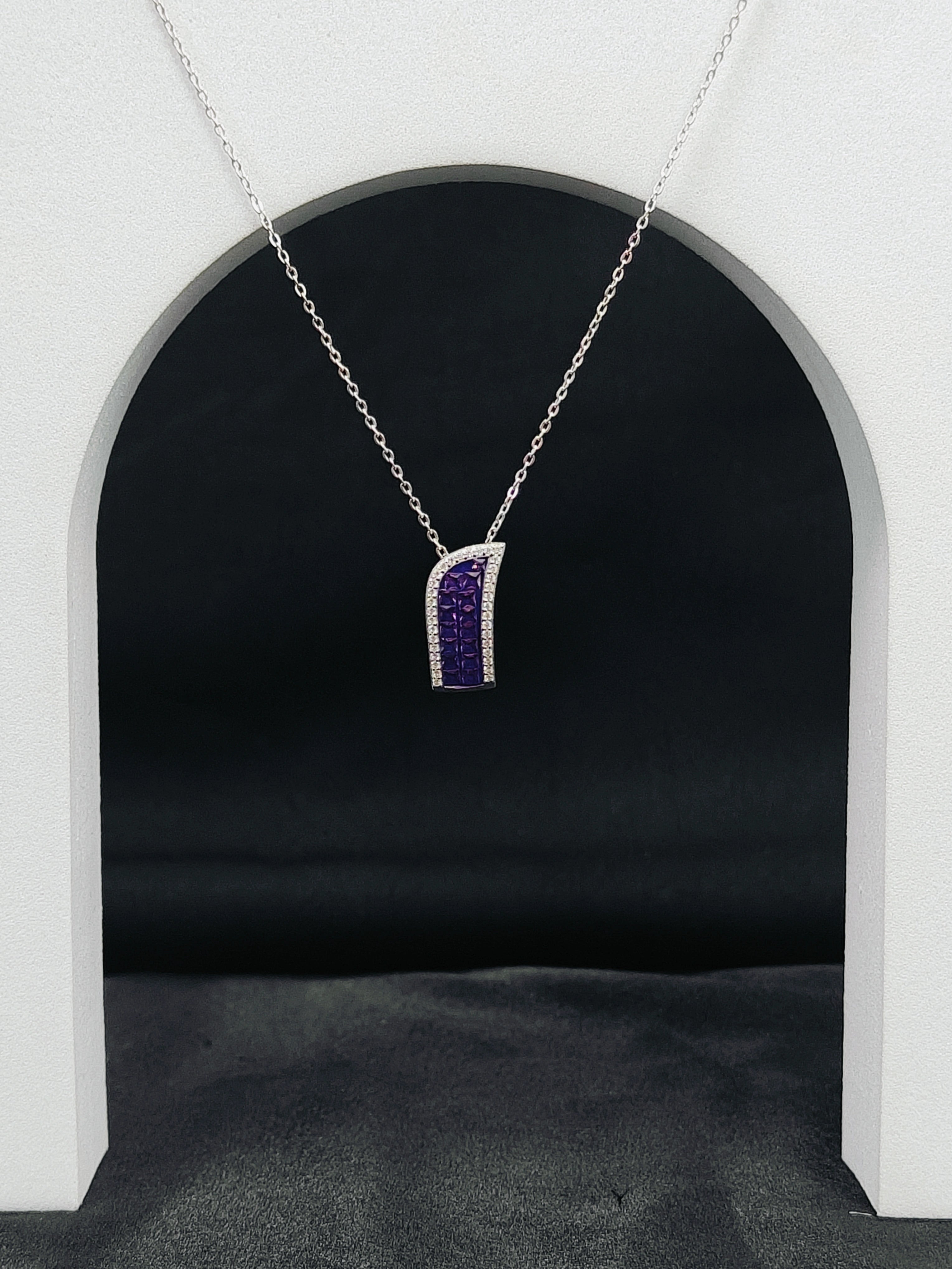 Silver necklace with a purple pendant hanging against a black background